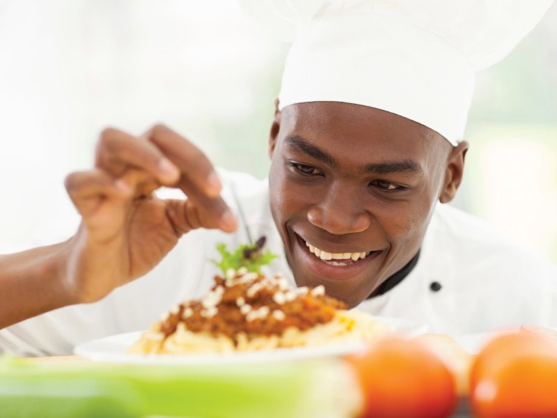 Chef garnishing a plate of red beans and rice